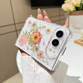 Back cover view of a hand holding the clear iPhone DUO case embedded with real pressed dry pink flowers, delicate stems, and holographic star glitter around the dual camera cutout.