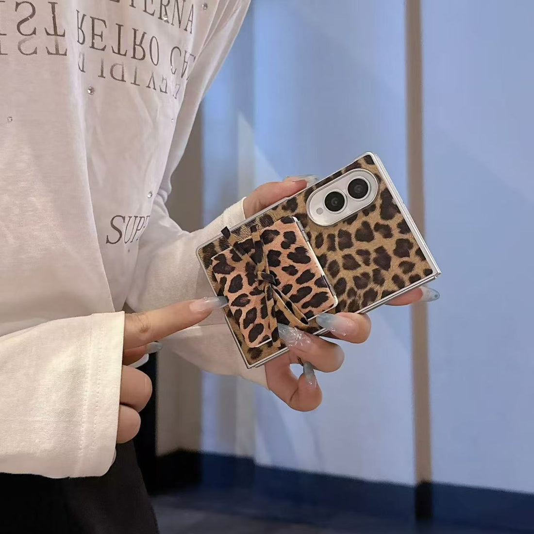 Close-up of hand pointing to cute tied bow detail on leopard print flip makeup mirror phone case