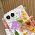 Close-up perspective of the dual camera cutout and elevated lens ring on the clear iPhone DUO case embedded with real pressed pink tulip petals and gold foil flecks.