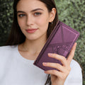 Close-up view of a model holding the metallic purple woven leather wallet phone case with secure magnetic closure clasp.