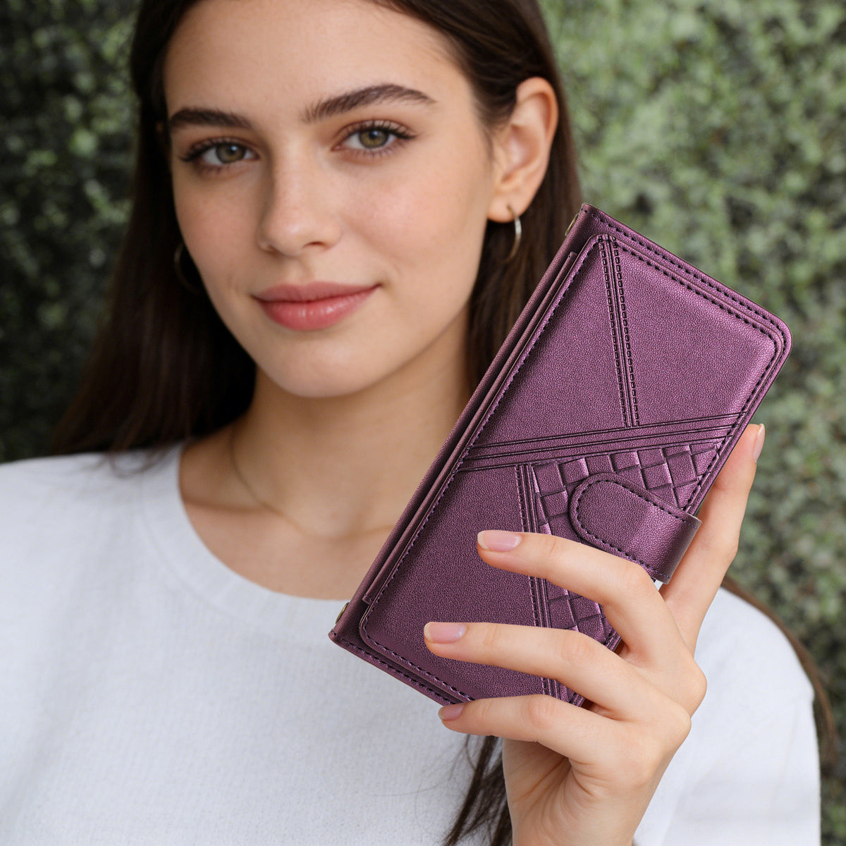 Close-up view of a model holding the metallic purple woven leather wallet phone case with secure magnetic closure clasp.