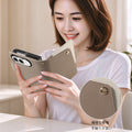 Close-up view of a model holding the taupe dual-tone leather iPhone DUO wallet case highlighting the fine textured leather grain and brass snap detail.