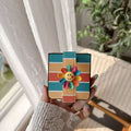 Close-up view of folded Galaxy Z Flip case featuring teal yellow coral stripes and a cute smiling flower charm.⁠