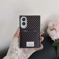 Close-up view of hand holding the black polka dot Samsung Galaxy Z Fold 8 case with built-in compact mirror cover.