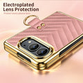 Close-up view of pink chevron quilted leather case for iPhone DUO highlighting raised electroplated gold camera lens bezel and gold finger ring clasp.