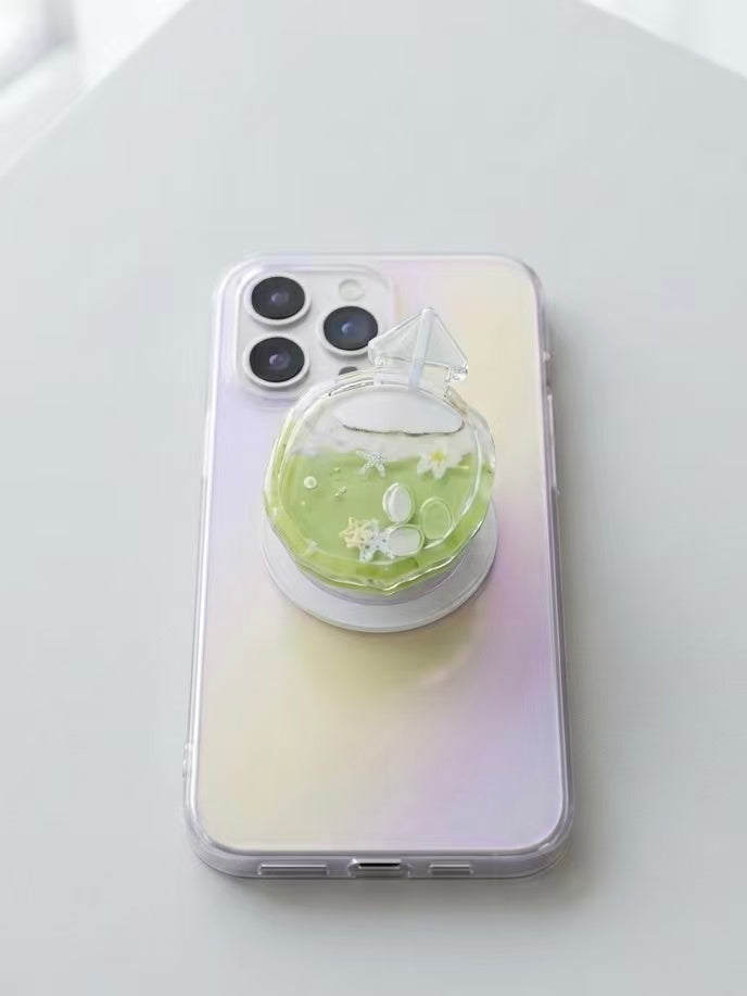 Close up view of clear faceted coconut cocktail phone grip showing shaker charms and magnetic base