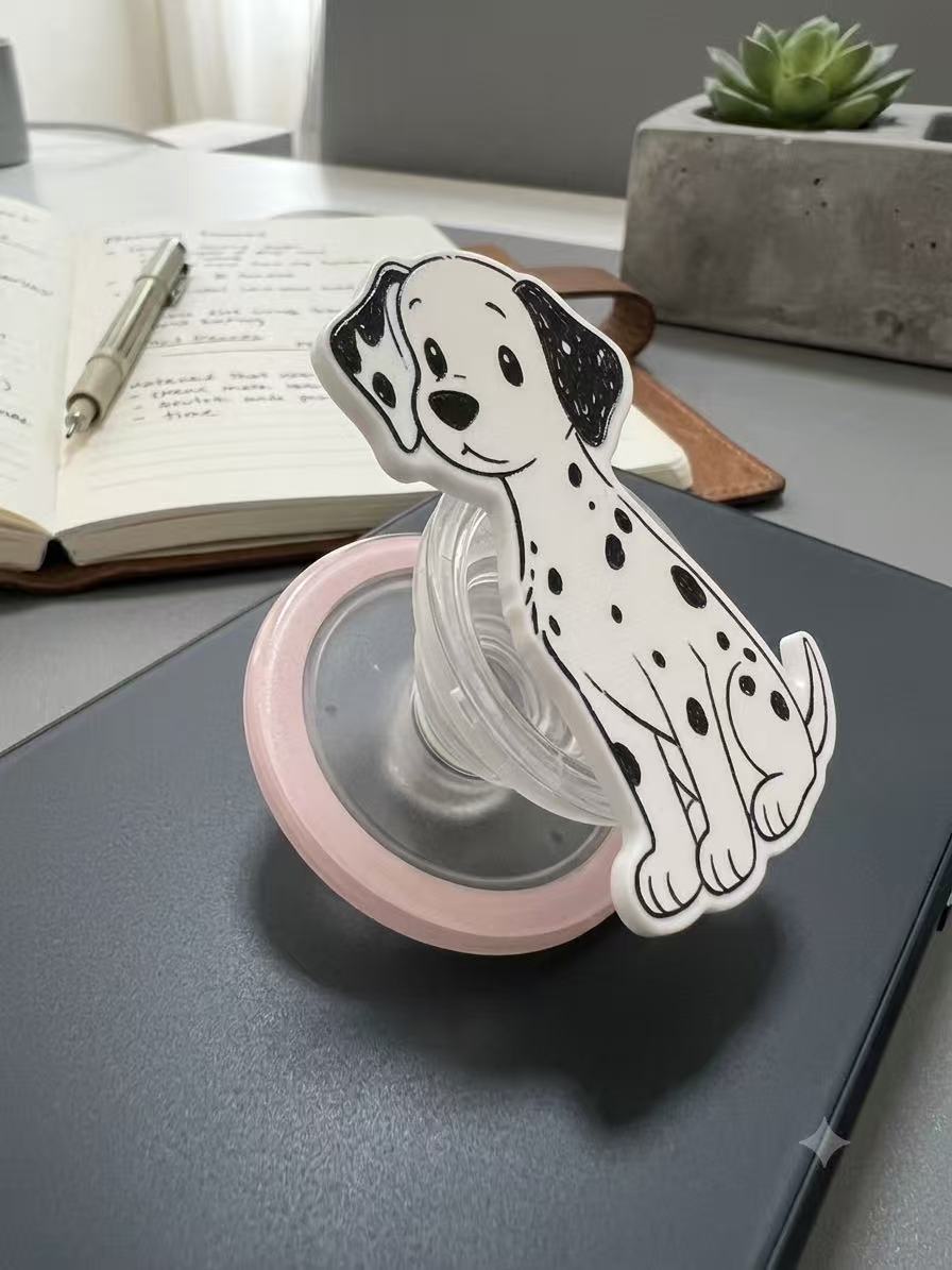 Dalmatian phone grip popped out, supporting a black smartphone horizontally on a wooden desk.