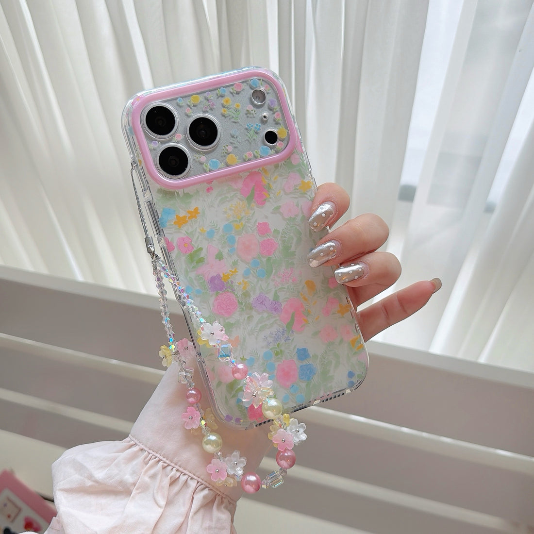 Cherry blossom floral phone case with beaded strap on iPhone showing soft pink flowers, cream pearls, and multi-color beads