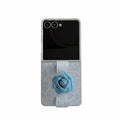 Denim texture case for Samsung Galaxy Z Flip featuring a 3D blue camellia flower finger strap loop on a white background.