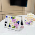 Elegant desk display of the open iPhone DUO clear case with real pressed garden flowers resting on a card next to a candle setting.