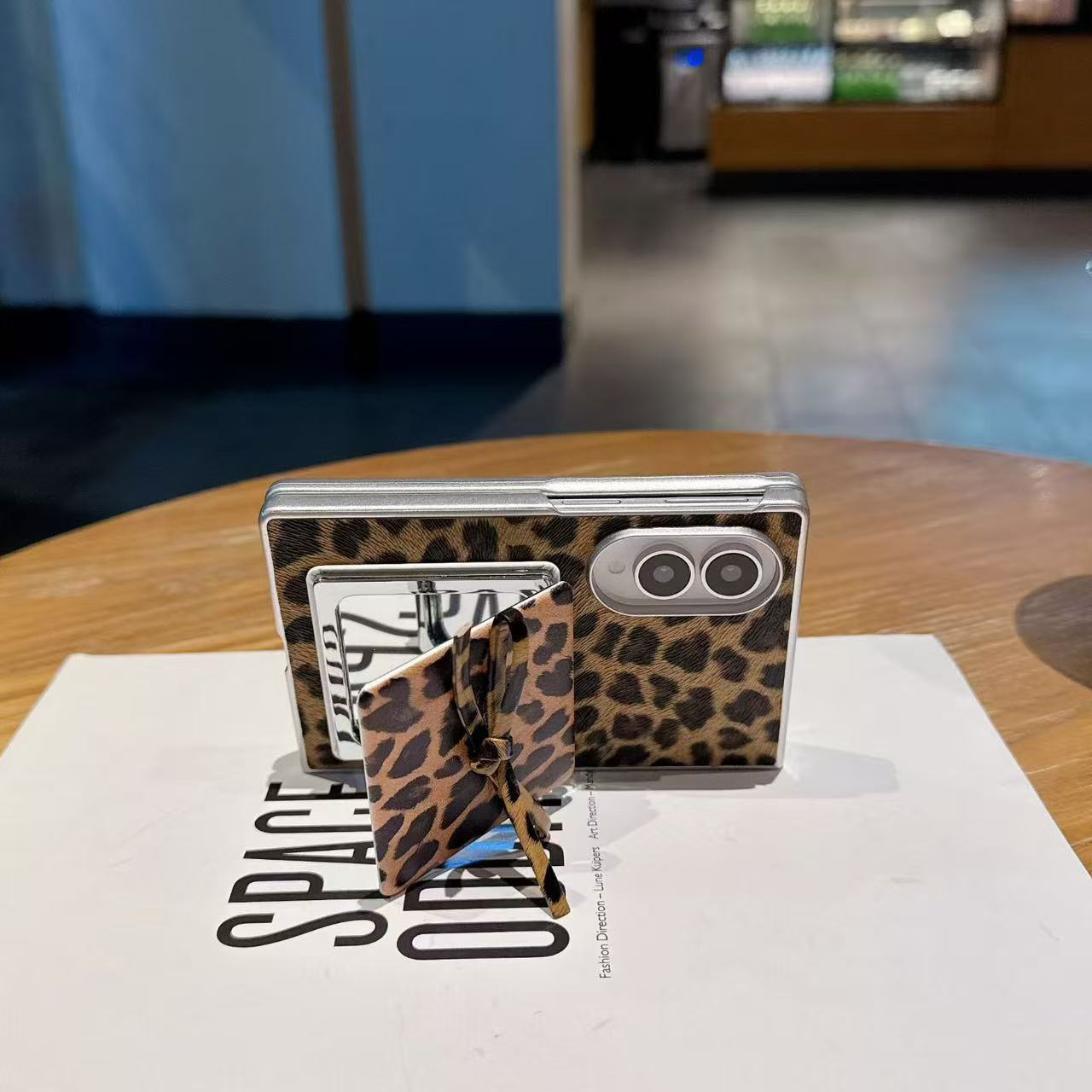 Folded Samsung Galaxy Z Fold standing horizontally with leopard print case and open flip makeup mirror kickstand