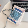 Folded Samsung Z Flip denim floral wristlet case resting on a laptop keyboard alongside aesthetic cards.