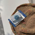 Folded Samsung Z Flip denim flower case displayed on top of an aesthetic wicker tray and magazine.