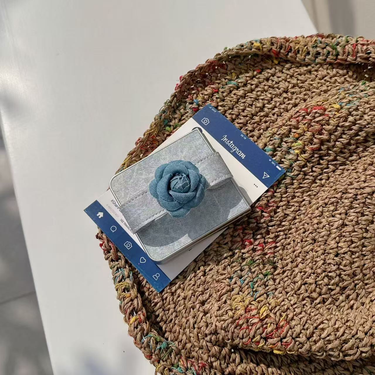 Folded Samsung Z Flip denim flower case displayed on top of an aesthetic wicker tray and magazine.