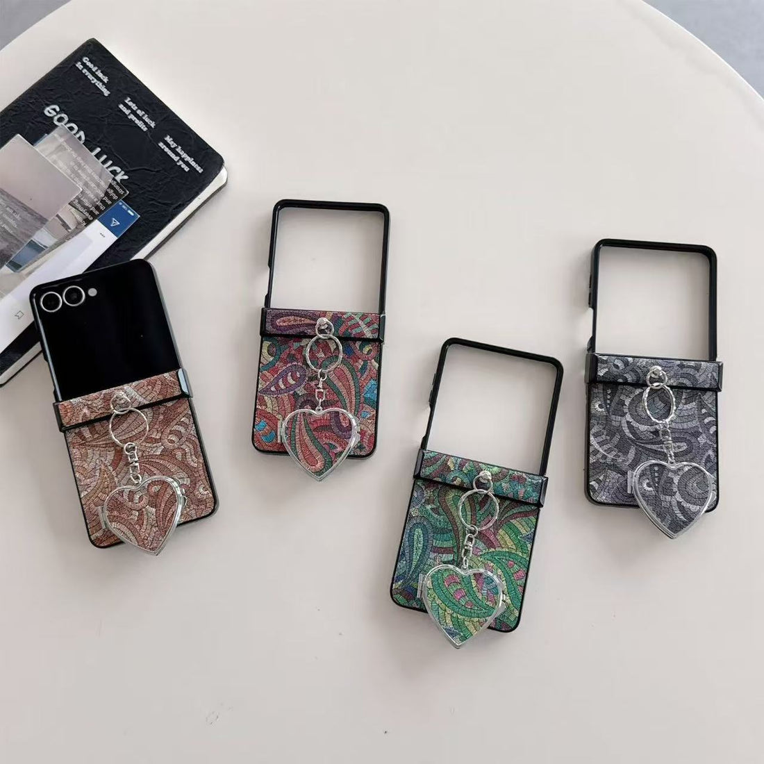 our colors of paisley textured Samsung Galaxy Z Flip cases displayed on a table in brown, multi-color, green, and charcoal gray with heart mirrors.