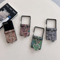 our colors of paisley textured Samsung Galaxy Z Flip cases displayed on a table in brown, multi-color, green, and charcoal gray with heart mirrors.