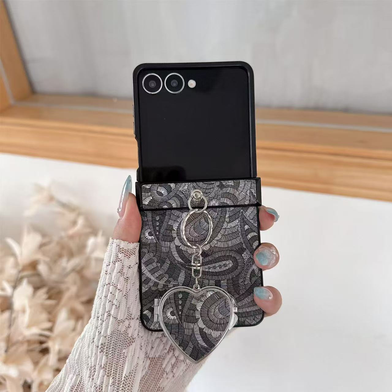Front-facing view of charcoal gray textured paisley Samsung Z Flip cover featuring silver heart compact mirror pendant.