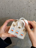 Hand holding cute house AirPods case demonstrating compact size and soft leather texture, portable earphone protection accessory