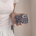 Hand holding a black and white monochrome paisley tapestry Samsung Galaxy Z Fold 8 case with silver heart mirror charm.