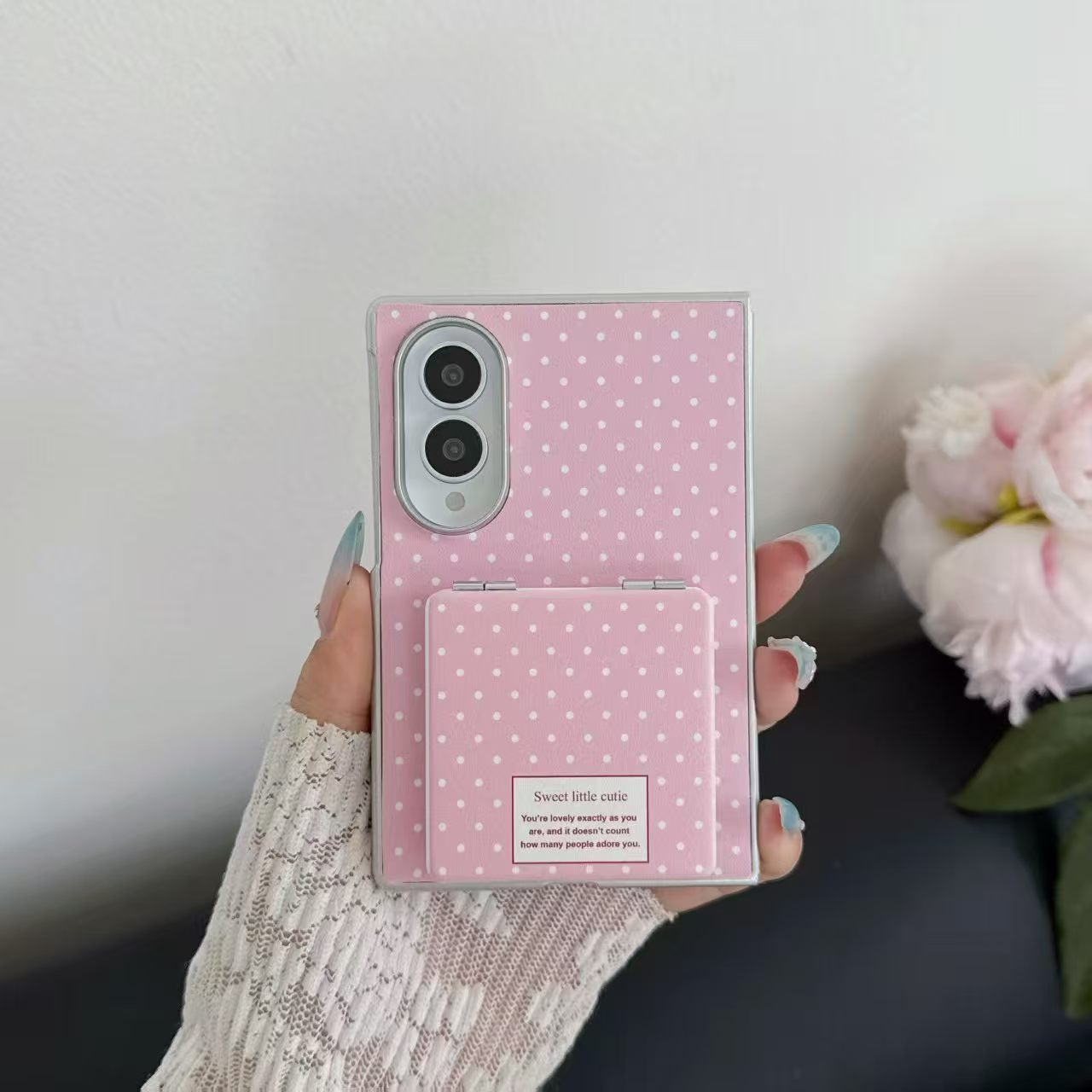 Hand holding the soft pink polka dot Samsung Galaxy Z Fold 8 phone case with closed mirror flap.