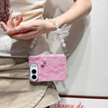 Hot pink glitter lace case for iPhone DUO held in hand showing front lock screen display, vibrant floral lace back texture, crystal bow charm, and attached pearl bow lanyard chain strap.