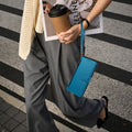 Lifestyle shot of a model carrying a cyan blue leather zipper wallet case for Samsung Galaxy using the wristlet lanyard strap while walking across a crosswalk.