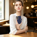 Model sitting in cafe holding navy blue luxury chevron leather Samsung Galaxy Z Fold 8 case with gold ring holder