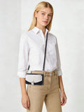 Model wearing the two-tone leather iPhone case with an adjustable long shoulder strap across the body.