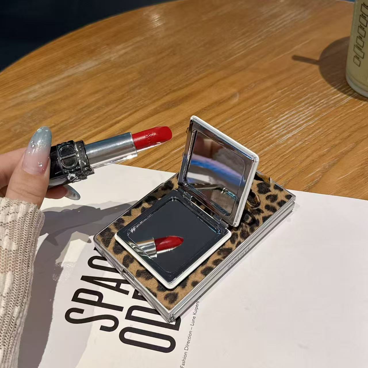 Open leopard print flip mirror phone case for Samsung Galaxy Z Fold resting on table with lipstick reflection in compact mirror