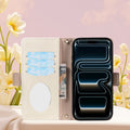 Open view of the cream interior of the dual-tone leather wallet case for iPhone, showing credit card slots, cash bill compartment, and integrated oval vanity mirror next to white flowers.