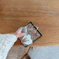 Person holding Samsung Z Flip phone in multi-color paisley case showing the open heart compact mirror with two glass mirrors inside.