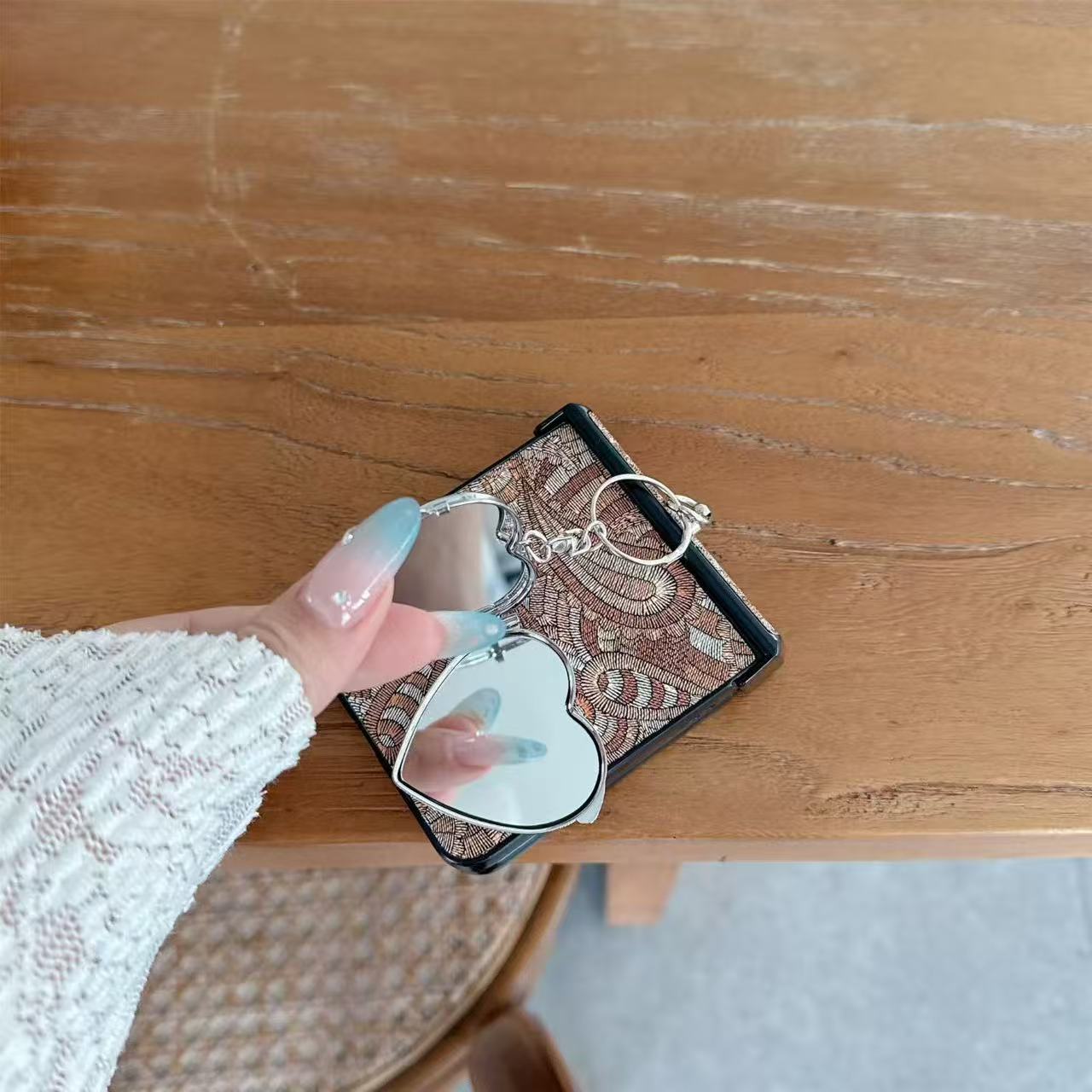 Person holding Samsung Z Flip phone in multi-color paisley case showing the open heart compact mirror with two glass mirrors inside.