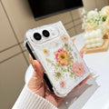 Perspective view of a hand holding the clear pressed flower and star glitter case for iPhone DUO, showing raised camera bezel protection and corner bumper frame.