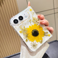 Perspective view of a hand holding the clear sunflower pressed flower case for iPhone DUO, showing raised camera bezel protection and corner bumper frame.