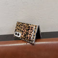 Semi-folded Samsung Galaxy Z Fold standing on a surface showcasing leopard print back cover and bow mirror accent