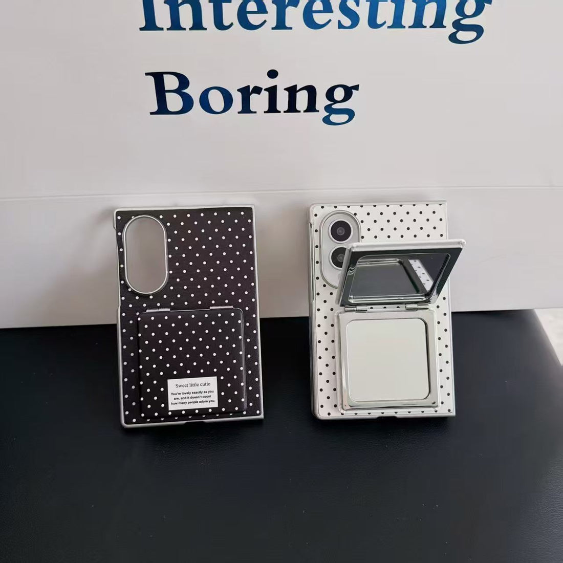 Three polka dot Samsung Galaxy Z Fold 8 phone cases in black, pink, and white with flip mirrors laid flat on a surface.