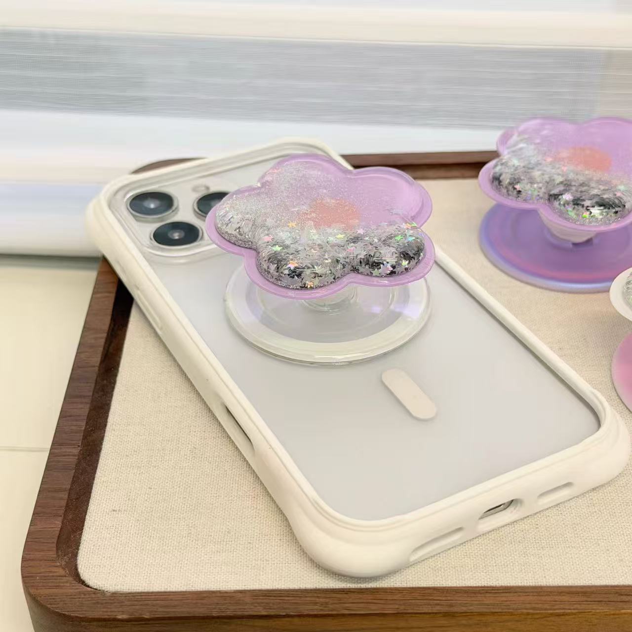 Magnetic translucent purple resin flower MagSafe phone grip expanded as kickstand on iPhone case.