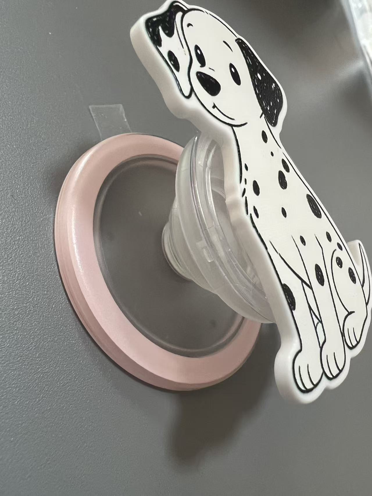 Side angle of expanded Dalmatian pop-out phone grip attached to a device.