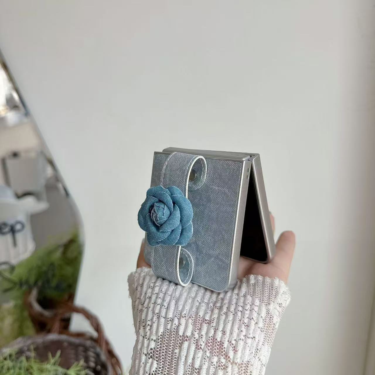 Side profile of partially open Samsung Z Flip phone displaying the 3D denim floral strap attachment.