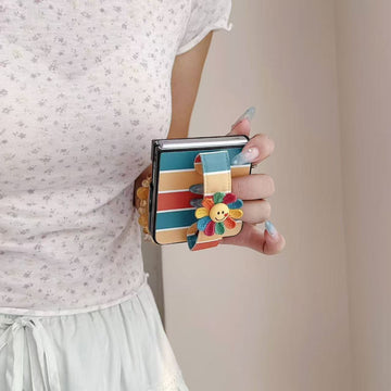 Side view of hand gripping a folded Samsung Z Flip phone using the integrated colorful flower hand strap