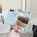 Sky blue marble swirl case for iPhone DUO held in hand displaying front lock screen display, 3D tied cord bow with pearl heart drops, raised dual-camera bezel, and attached blue leather pearl-lined lanyard wristlet strap.