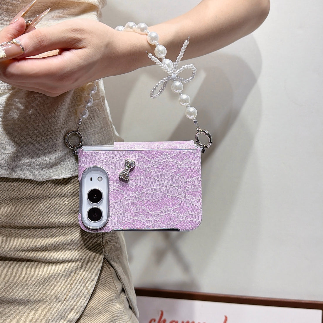 Collection of iPhone DUO lace cases with pearl bow chain straps laid out in four available colors including hot pink, light pink, white, and soft lavender.