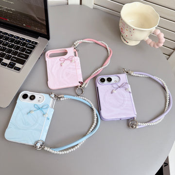 Three color variants of the iPhone DUO marble swirl cases in soft pink, sky blue, and lavender purple laid out on a table with matching pearl lanyard wristlet straps.