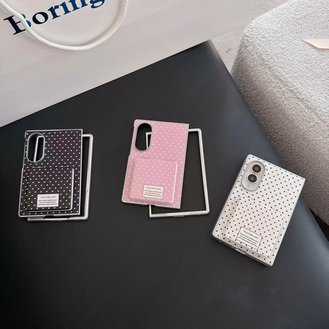 Three polka dot Samsung Galaxy Z Fold 8 phone cases in black, pink, and white with flip mirrors laid flat on a surface.