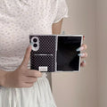 Unfolded Samsung Galaxy Z Fold 8 phone held in hands showing the full inner main screen and black polka dot back cover.