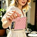 Woman carrying pink iPhone DUO leather case outdoors holding it securely by the attached gold finger ring strap.