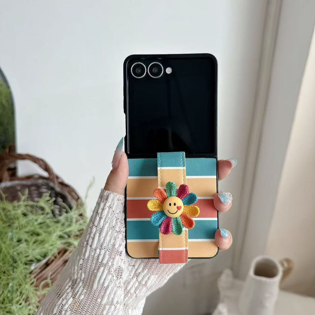 Side view of hand gripping a folded Samsung Z Flip phone using the integrated colorful flower hand strap
