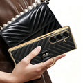 Woman holding black luxury chevron leather ring case for Samsung Galaxy Z Fold next to matching handbag