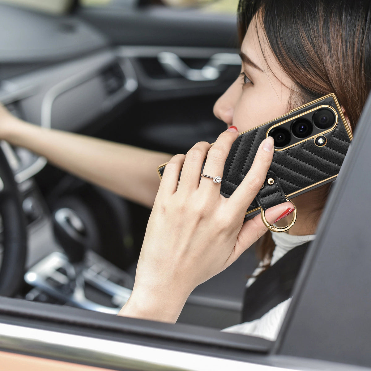 Woman making a phone call in a car holding black chevron leather Samsung Galaxy Z Fold case with gold ring