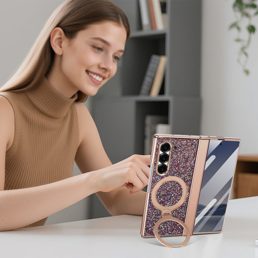 Woman using a Samsung Galaxy Z Fold phone supported in landscape mode by the 360-degree rotating ring kickstand on a rose gold glitter case.
